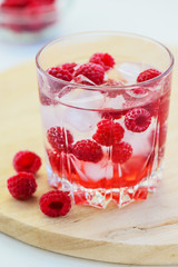 Refreshing drink with raspberries and ice. Lemonade on a white table, vertical orientation