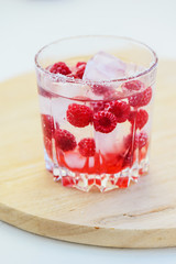 Refreshing drink with raspberries and ice. Lemonade on a white table, vertical orientation