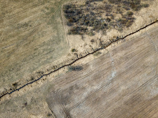 aerial view of small country river bed wavy in spring time in countryside