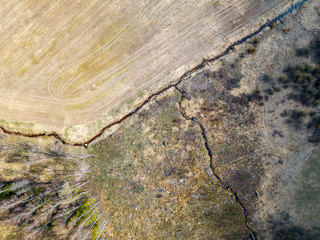 aerial view of small country river bed wavy in spring time in countryside