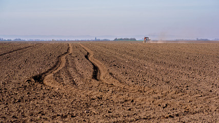 Tractor spraying a soil with fertilizer. Fertilization of soil. Early spring time.