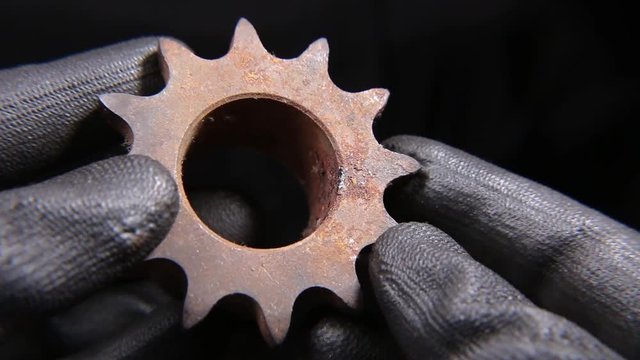 Someone holding a heavy machine part in hand wearing gloves