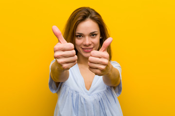Young pretty young woman with thumbs ups, cheers about something, support and respect concept.