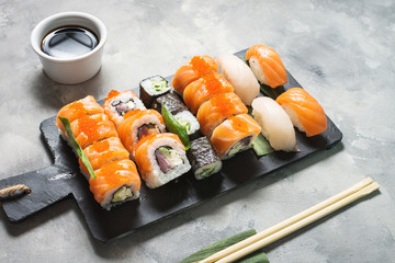 Various kinds of sushi served on concrete background.