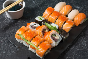 Various kinds of sushi rolls served on stone background.