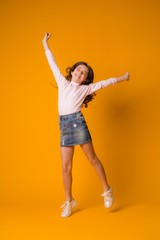 Fototapeta na wymiar kid girl jumping happy girl dancing on yellow background
