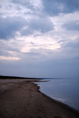 calm sea beach on the shore of Baltic sea with blue clouds and low tide