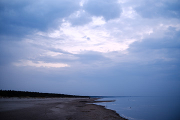 calm sea beach on the shore of Baltic sea with blue clouds and low tide