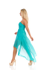 Fashion Model In Turquoise Dress Is Walking And Looking Away