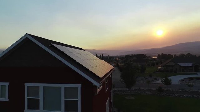 Aerial dolly shot of solar panels at sunrise with smoke from wildfires