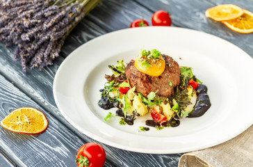 Beef cutlet with mashed potatoes, garnished with microgreens, tomatoes and egg yolk