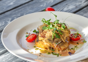Beef steak on golden crispy potatoes with cheese and tomatoes