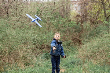 The boy launches a blue plane into the sky in a dense forest - 265684886