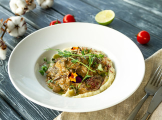 Chicken livers in a creamy sauce with mushrooms and mashed potatoes, decorated with green earth and flowers on a served table