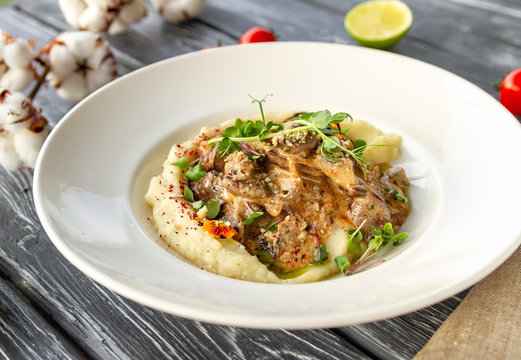 Chicken liver in creamy sauce with mushrooms and mashed potatoes, decorated with microgreen and flowers