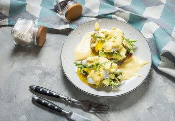 Eggs Benedict with avocado on concrete background.