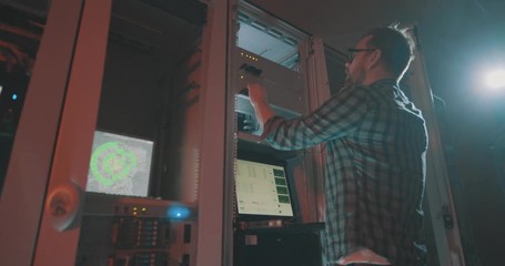 Young male programmer in eyeglasses talking smartphone