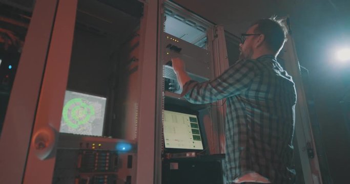 Young male programmer in eyeglasses talking smartphone