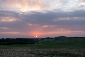 Evening scenery in the countryside, all the sky is in sunset colors and there is a red sun