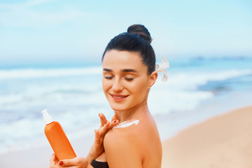 Suntan Lotion. Sexy Young Woman in Bikini  Applying Sunscreen Solar Cream.Sun Protection. Sun Cream. Skin and Body Care.Girl Holding Moisturizing Sunblock. Sun shape on the shoulder. Skin Protection