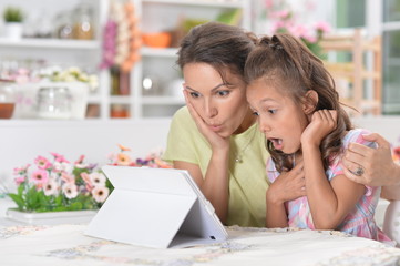Portrait of surprised mother and daughter using modern tablet