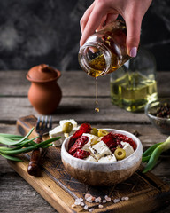 Greek cheese feta with herbs and olives, sundried tomatoes. Bulgarian cheese. Feta in oil. Olove oil. selective focus. appetizer