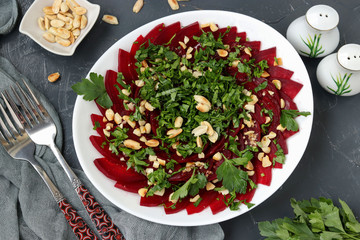 Healthy beetroot salad with peanuts and parsley on a white plate
