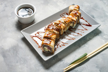 Golden dragon sushi roll served on concrete background.
