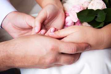 couple sitting holding hands with woman's hand on top of man's hand