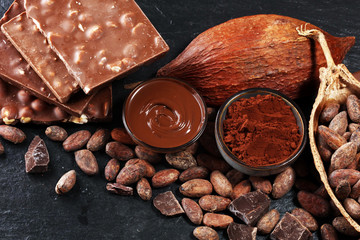 Melting chocolate or melted chocolate with a chocolate swirl and stack, chips and powder on black