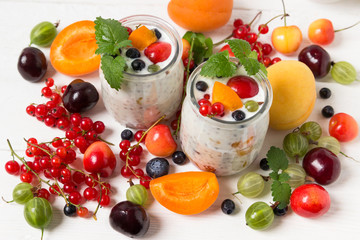 Fresh yogurt with chia seeds. Currants, cherries, gooseberries, apricots and blueberries on a white table.