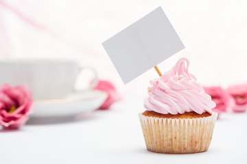 selective focus of delicious pink cupcake decorated with sprinkles and blank card
