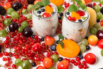 Fresh yogurt with chia seeds. Currants, cherries, gooseberries, apricots and blueberries on a white table.