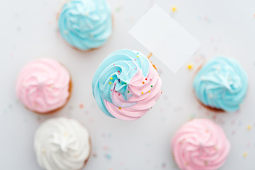 top view of delicious pink, white and blue cupcakes with sprinkles and blank card Isolated On White