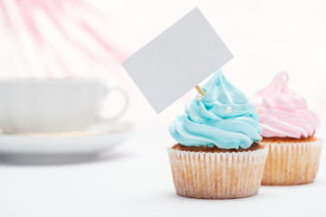 selective focus of tasty cupcakes decorated with sprinkles and blank card