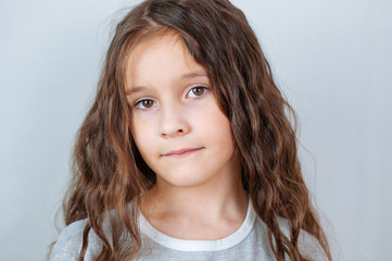 Studio emotional portrait of a serious little girl with long hair