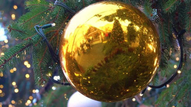 Reflection (New Year's fair) in a glass ball on a new year tree. fixed camera