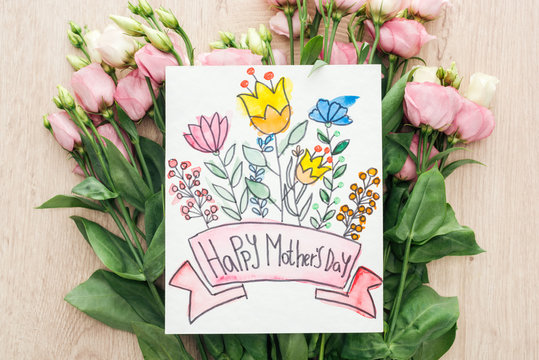 top view of eustoma flowers and card with happy mothers day lettering on table