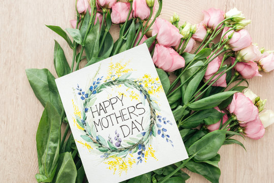 top view of pink eustoma flowers and card with happy mothers day lettering on table