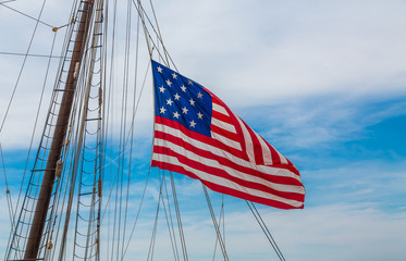 An American flag flying from the riggings of a tall ship