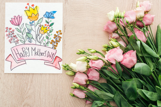 top view of eustoma flowers and card with happy mothers day lettering on table