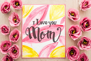 top view of eustoma flowers and card with i love you mom words on wooden table