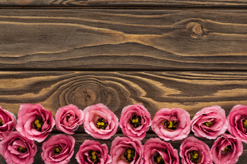top view of arranged pink eustoma flowers on wooden table with copy space