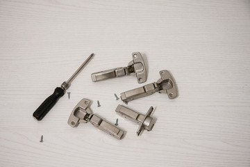 Furniture assembly. Works indoors. Metal fittings and screwdriver for mounting in a box on a wooden background.