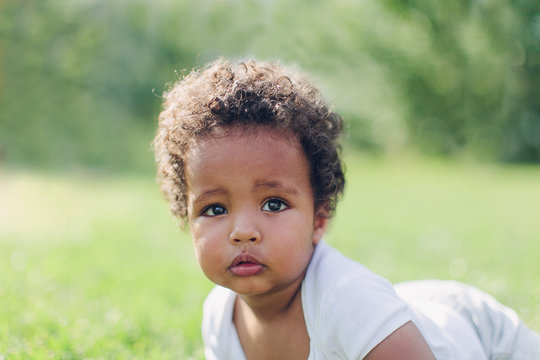 little african american boy lying in the park on the grass
