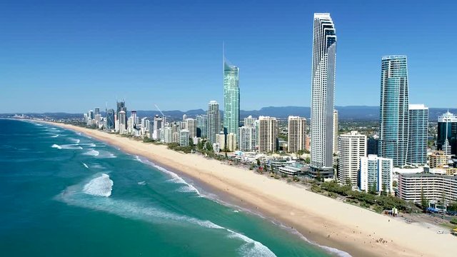 Static aerial shot of the skyscrapers and slow waves hitting the beaches of Surfers Paradise Gold Coast Queensland Australia