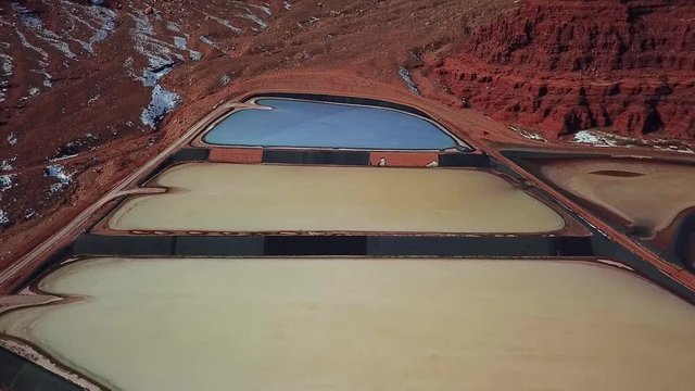 Aerial, reverse, drone shot, tilting up above colorful tailing ponds for mineral waste in rural Utah mines, United States of America