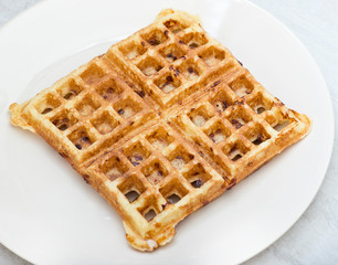 Homemade square belgian waffle on white plate