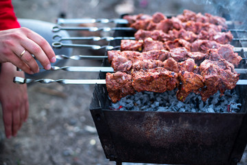 in male hands a skewer with meat, shashliks and onions