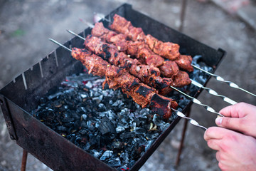 in male hands a skewer with meat, shashliks and onions